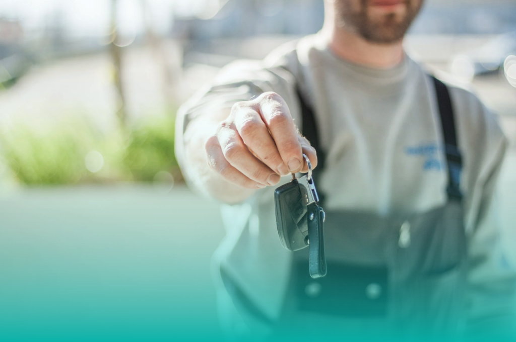 Blurred car dealer holding out car keys in focus as if offering you the keys to a new vehicle. 