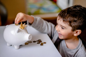 Kid putting money in piggy bank