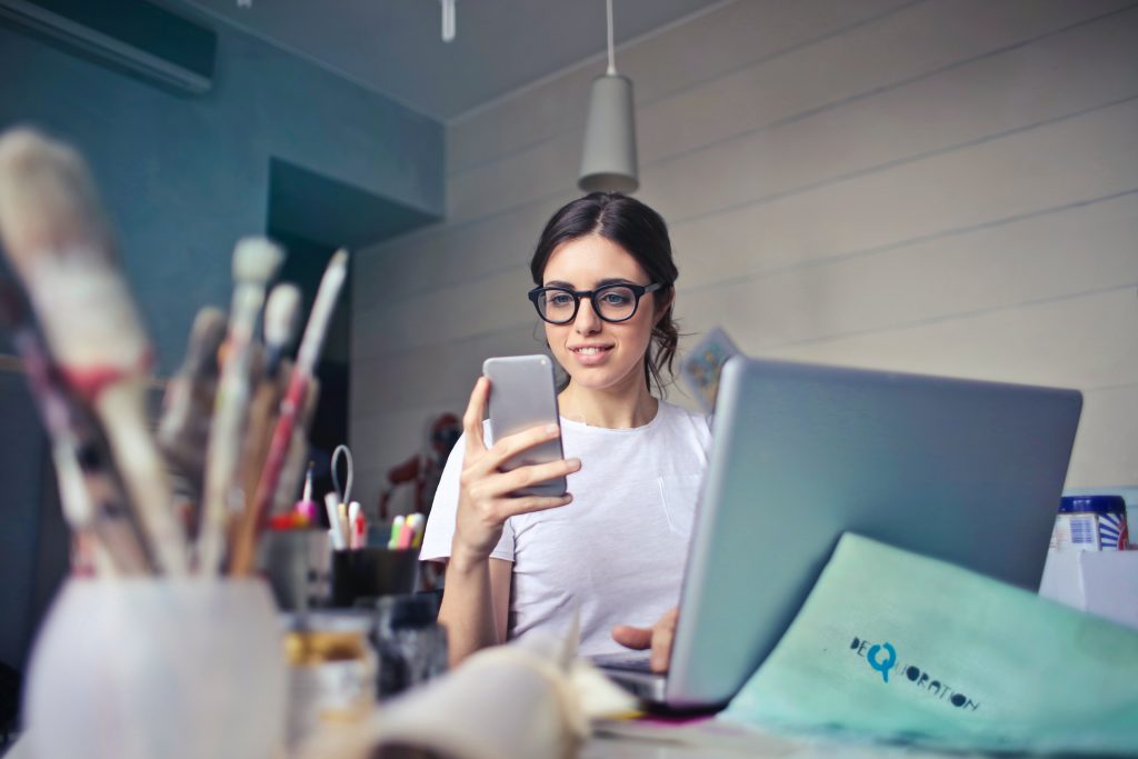 woman on mobile phone working at laptop